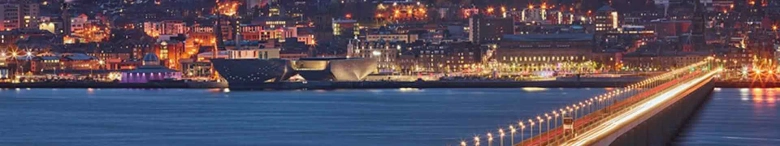 Panoramic night view of Dundee cityscape with illuminated buildings and the River Tay.