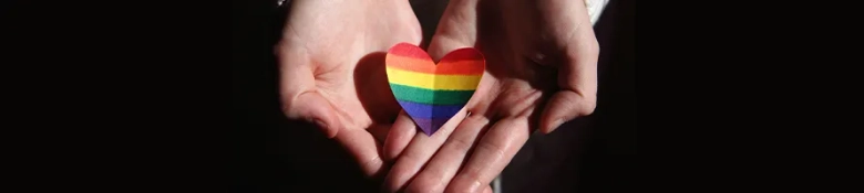 Hands holding a rainbow heart: find out about LGBTQ+ support in the workplace