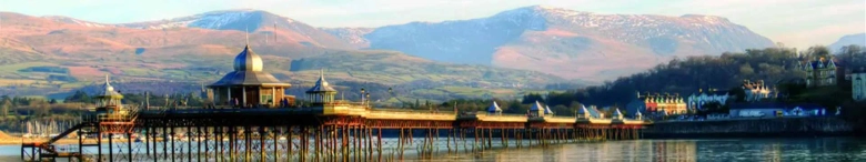 Panoramic view of Bangor Pier with Snowdonia mountains in the background.