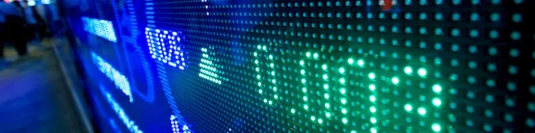 Blurred view of a stock market LED ticker board displaying financial data.